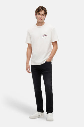 Zwarte slim jeans van TOMMY JEANS, gedragen door een man met een crèmekleurig T-shirt en witte sneakers.