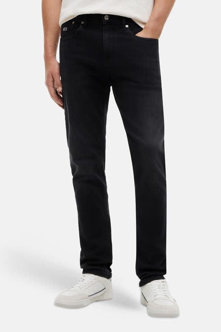 Zwarte slim jeans van TOMMY JEANS van denim met lichte vervaging, gedragen met een wit T-shirt en witte sneakers.