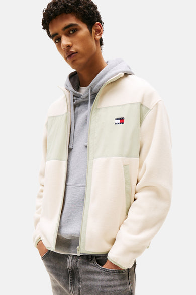 Beige fleece jas van TOMMY JEANS, met lichtgroene accenten en grijze hoodie eronder.

