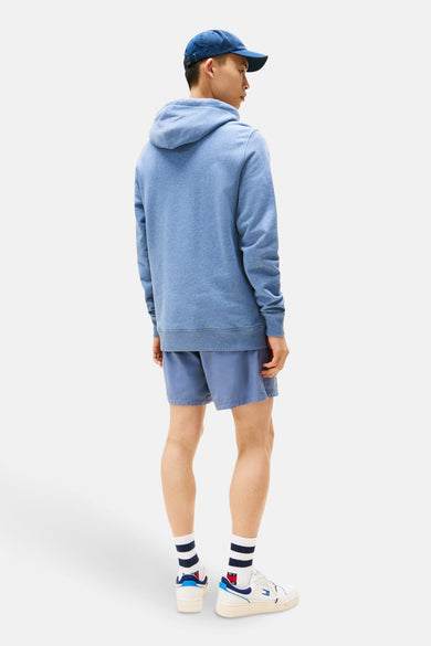 Blauwe sweater met kap van TOMMY JEANS, met bijpassende shorts, gestreepte sokken en witte sneakers.