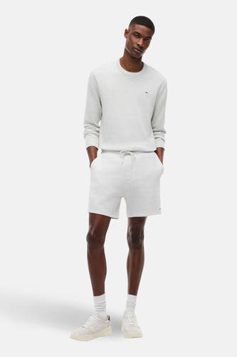 Grijze short van TOMMY JEANS, met trekkoord, in combinatie met een sweater, sokken en sneakers.

