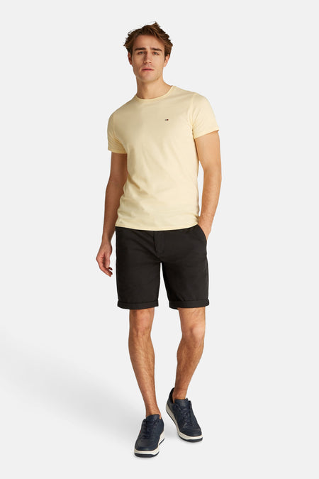 Zwarte short van TOMMY JEANS, gecombineerd met een geel T-shirt en blauwe schoenen.