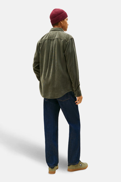 Groen hemd van TOMMY JEANS, met lange mouwen, gedragen met een bordeauxrode muts en donkerblauwe jeans.