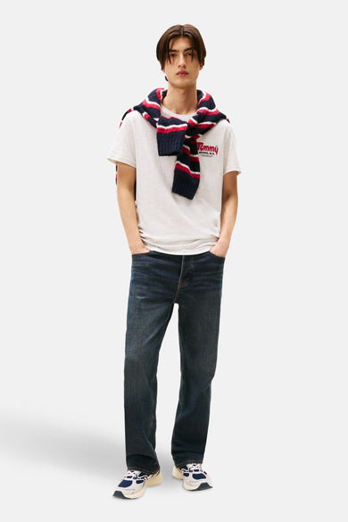 T-shirt gris à manches courtes de TOMMY JEANS, avec un pull rayé noué lâchement sur les épaules.