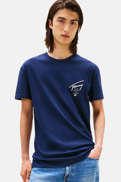 T-shirt bleu à manches courtes de TOMMY JEANS, avec une impression blanche sur la poitrine, porté avec des jeans.