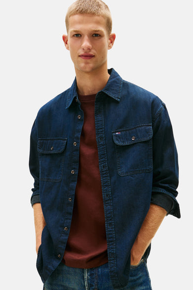 Donkerblauw jeanshemd van TOMMY JEANS, met lange mouwen en gedragen over een bordeauxrood T-shirt, in close-up.
