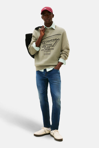 Donkerblauwe tapered jeans van TOMMY JEANS, gecombineerd met een trui en witte sneakers voor een casual look.
