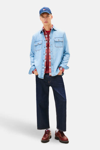 Jeanshemd van mid blue denim van TOMMY JEANS, gedragen over een rood geruit overhemd, met een blauwe pet.