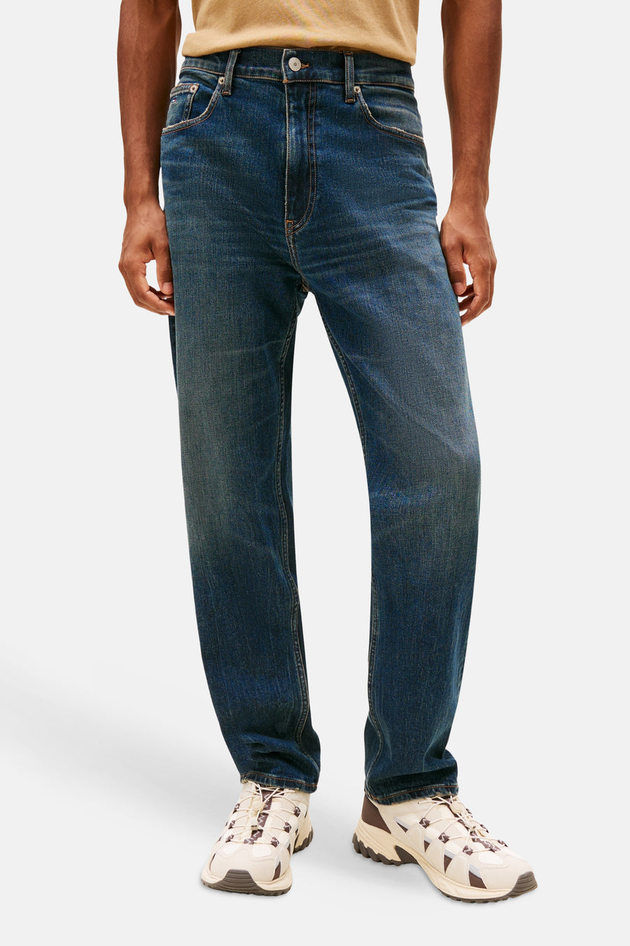 Tapered jeans van donkerblauw denim van Tommy Jeans, met een normale taille en beige-bruine sneakers.
