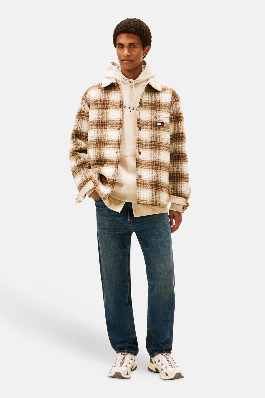 Tapered donkerblauwe jeans van TOMMY JEANS, met een casual pasvorm en gedragen met een hoodie en een geruit overhemdjack.
