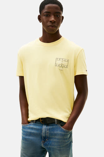 T-shirt jaune à manches courtes de TOMMY JEANS, avec imprimé sur le dos, associé à des jeans larges.