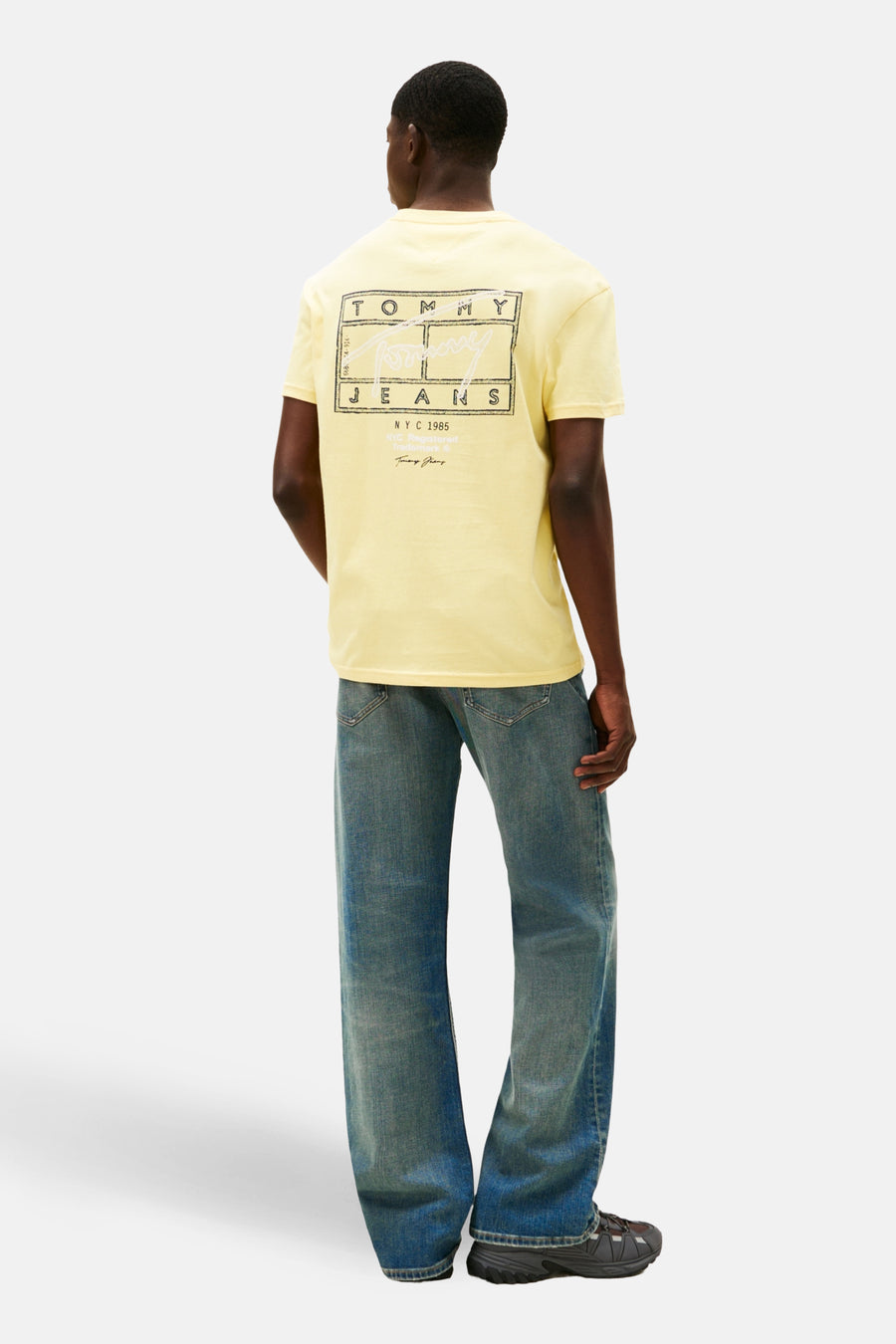 Man in gele T-shirt en blauwe jeans.