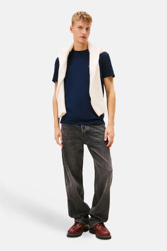 Blauw T-shirt met korte mouwen van TOMMY JEANS, met een witte trui losjes over de schouders.