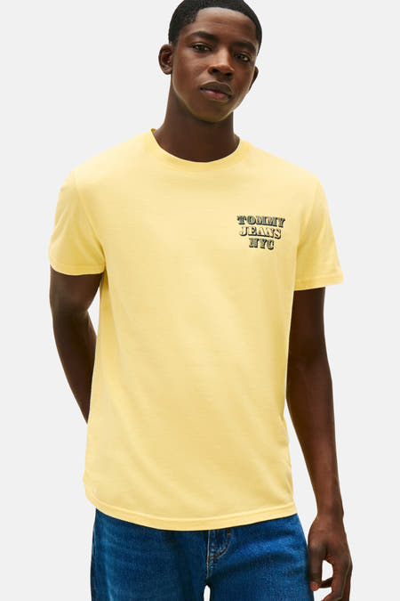 Geel T-shirt met korte mouwen van TOMMY JEANS NYC, met een klein logo op de borst en gedragen met een donkerblauwe jeans.
