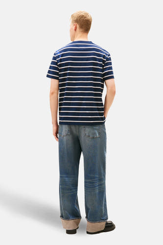 Blauw T-shirt met korte mouwen van TOMMY JEANS, met een gestreept patroon, gedragen met een losse jeans.
