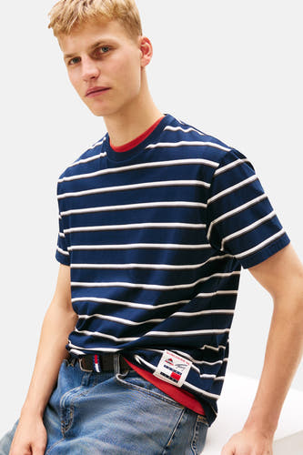 Blauw gestreept T-shirt met korte mouwen van TOMMY JEANS, met een rode kraag en een merklabel op de zoom, gedragen met jeans en een riem.