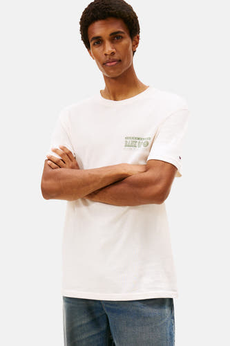 Wit T-shirt met korte mouwen van Tommy Jeans, met een groene print op de borst, gedragen met een blauwe jeans.
