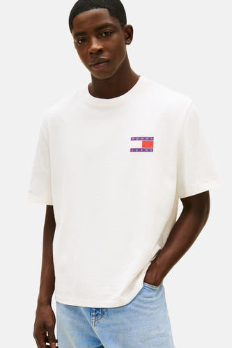 T-shirt blanc à manches courtes de Tommy Jeans, avec un châle sur les épaules et des jeans bleu clair.