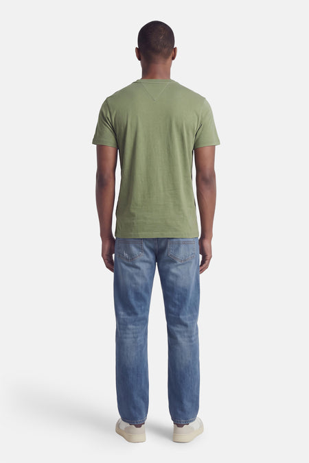 Groene korte mouwen t-shirt van TOMMY JEANS, achterzijde weergegeven, eenvoudig ontwerp, gedragen met blauwe jeans en witte sneakers