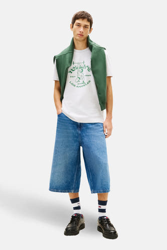 Grijs T-shirt met korte mouwen van Tommy Jeans, met groene gymprint, gecombineerd met denim culottes en groene sweater over de schouders.