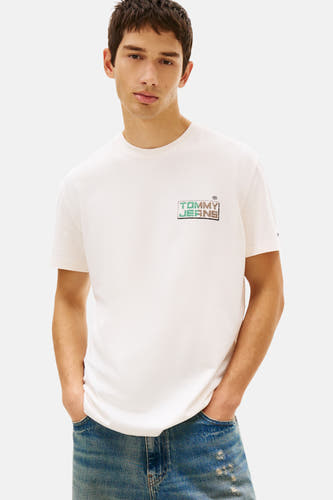 Ecru T-shirt met korte mouwen van TOMMY JEANS, met een logo op de borst en gedragen met een spijkerbroek.
