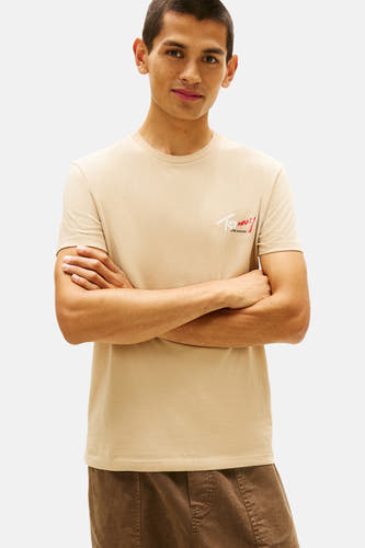 T-shirt beige à manches courtes de TOMMY JEANS, avec un cardigan noir noué lâchement sur les épaules.
