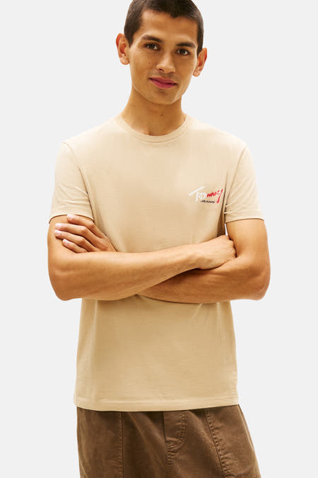Beige T-shirt met korte mouwen van TOMMY JEANS, met logo op de borst en bruine broek.