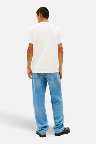 Wit T-shirt met korte mouwen van TOMMY JEANS, gezien van achteren, gecombineerd met losse jeans en zwarte schoenen.