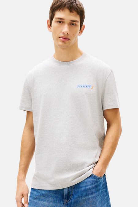 T-shirt gris à manches courtes de TOMMY JEANS, avec petit logo sur la poitrine et porté avec un short en jean ample.