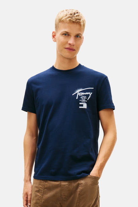 Blauw T-shirt met korte mouwen van TOMMY JEANS, met witte logo-opdruk op de borst, gedragen met een bruine broek.