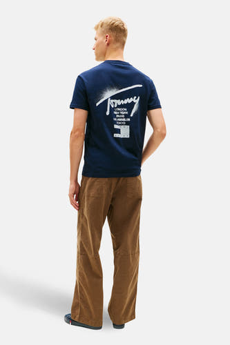 Blauw T-shirt met korte mouwen van TOMMY JEANS, met print van steden en bruine broek.
