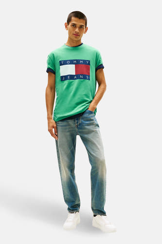 Groen T-shirt met korte mouwen van TOMMY JEANS, met een logo op de borst, gecombineerd met jeans en witte sneakers.

