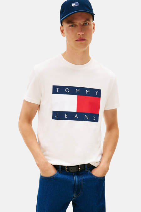 Wit T-shirt met korte mouwen van TOMMY JEANS, met logo op de borst en gedragen met jeans en pet.

