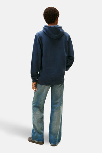 Blauwe sweater met kap van TOMMY JEANS, met lange mouwen en combineerd met een jeans en schoenen.
