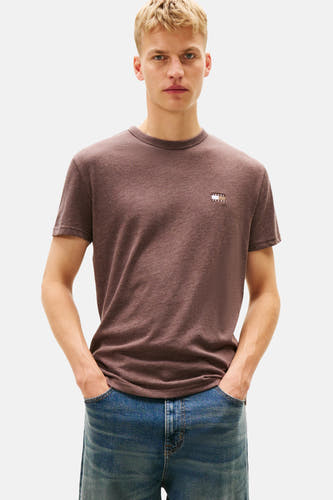 T-shirt brun à manches courtes de TOMMY JEANS, porté par le modèle avec un jeans large.