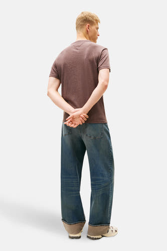 Bruin T-shirt met korte mouwen van TOMMY JEANS, met model van achteren gezien in wijde jeans.
