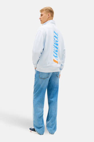 Pull bleu à col roulé de TOMMY JEANS, avec imprimé logo TOMMY vertical au dos, à combiner avec un jean et des baskets basses.