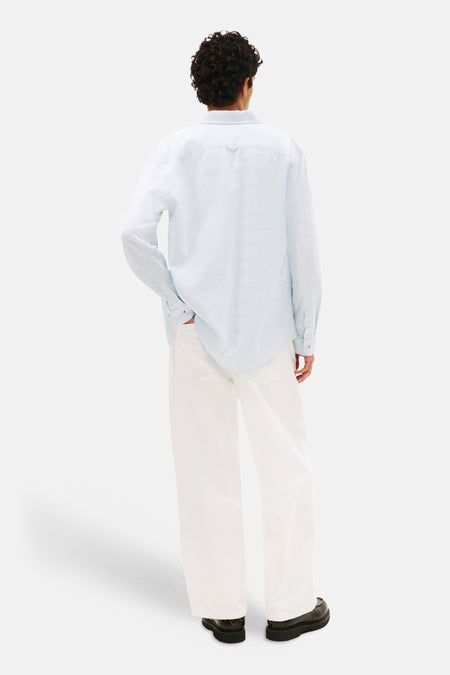 Chemise bleue TOMMY JEANS, vue de dos, à manches longues et pantalon blanc.