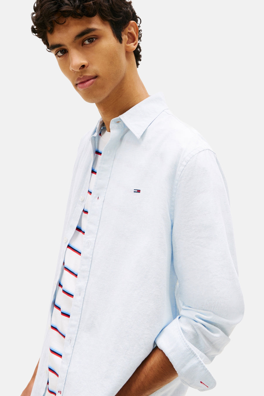 Blauw hemd van TOMMY JEANS met lange mouwen, gedragen over een gestreept T-shirt.