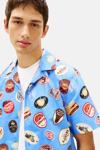 Blauw overhemd met korte mouwen van Tommy Jeans, met een fruit- en logo-etikettenpatroon.
