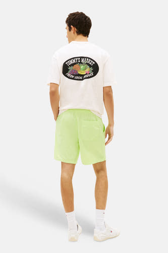 Limegroene short van TOMMY JEANS met licht glanzende, kreukelige stof, gedragen door een man van achteren gezien.