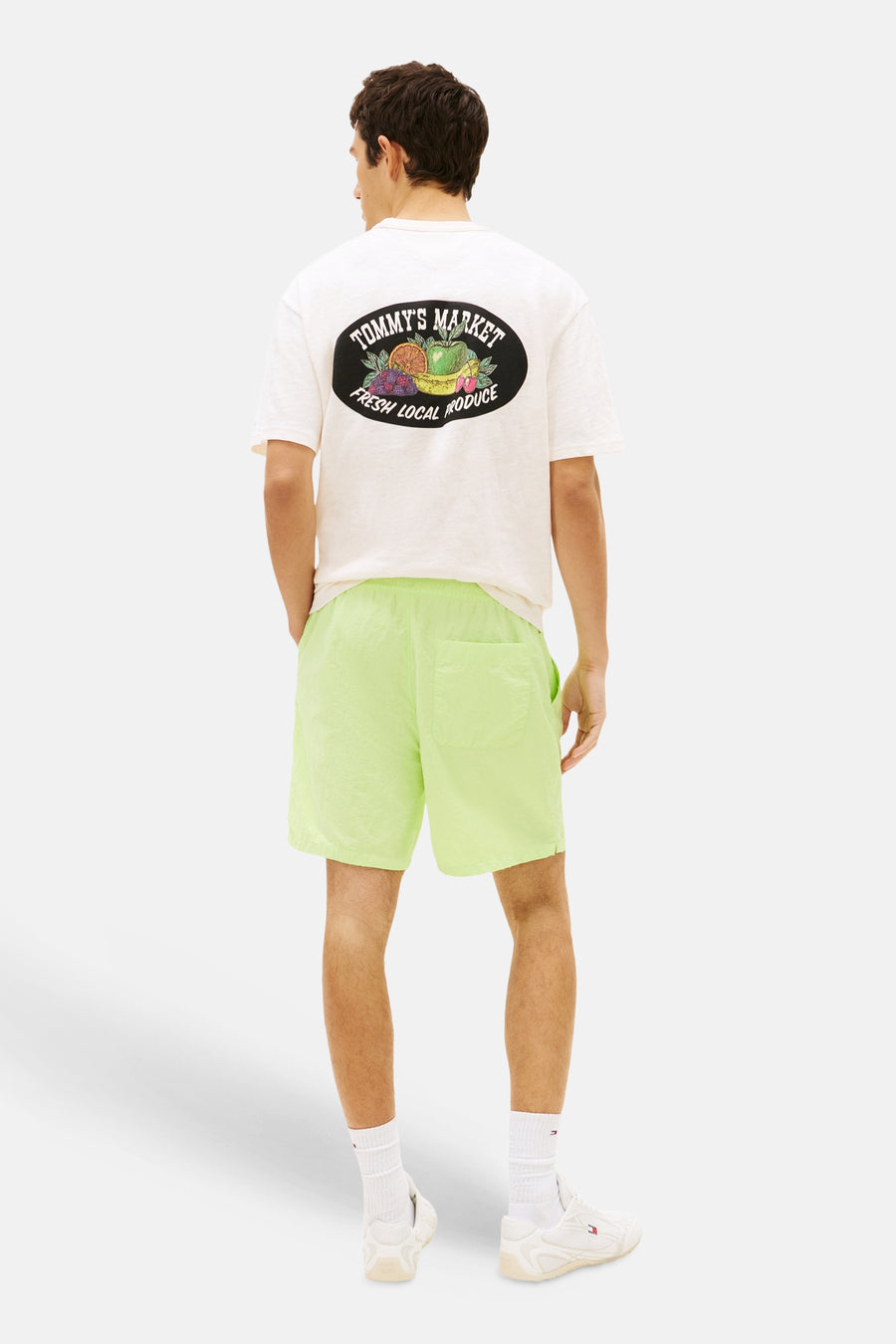 Limegroene short van TOMMY JEANS met licht glanzende, kreukelige stof, gedragen door een man van achteren gezien.