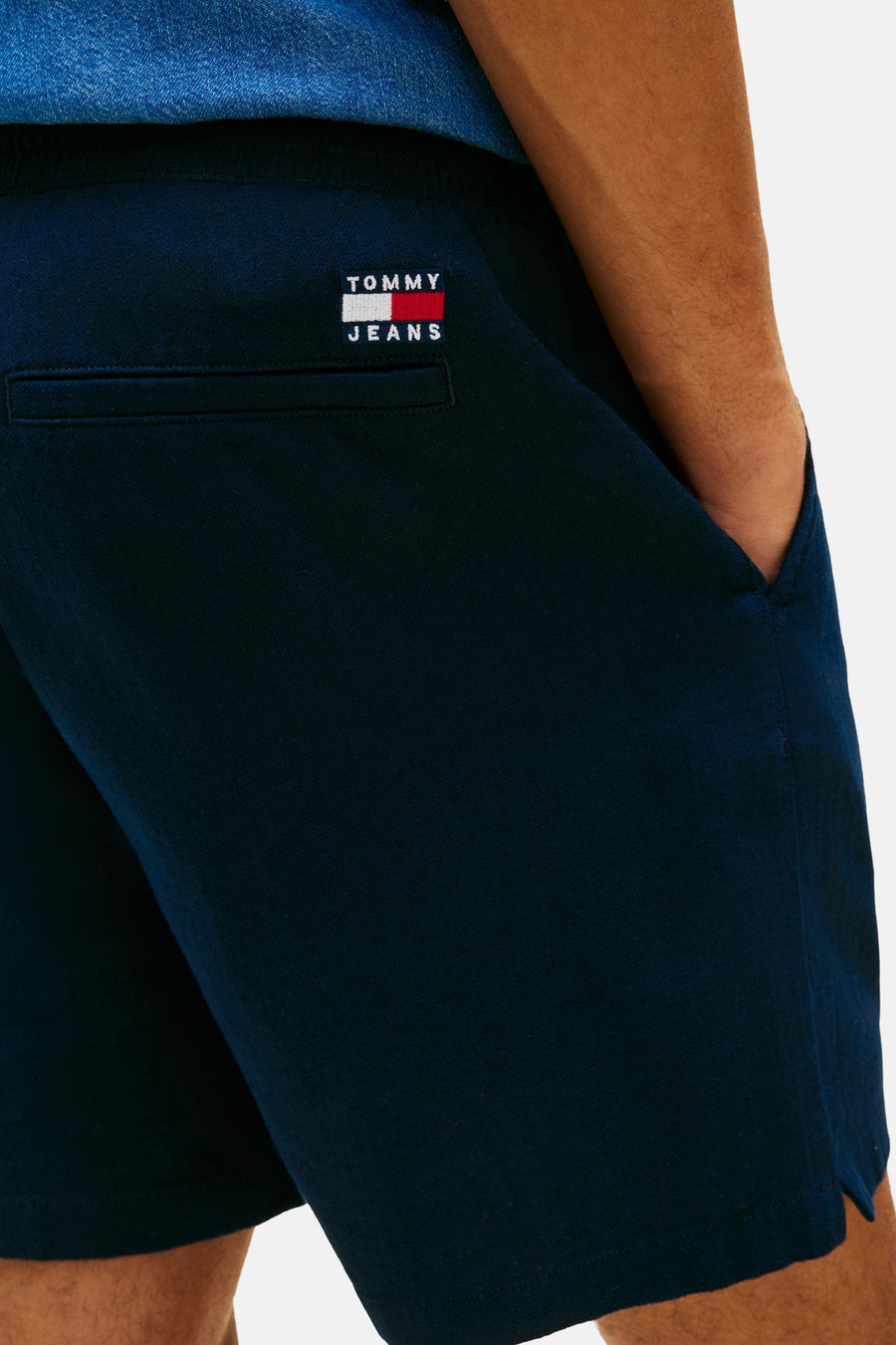 Blauwe short van TOMMY JEANS, met achterzak en hand in de steekzak.
