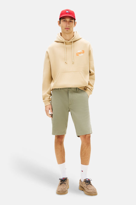 Groene short van TOMMY JEANS, gecombineerd met een beige hoodie, witte sokken en bruine schoenen.