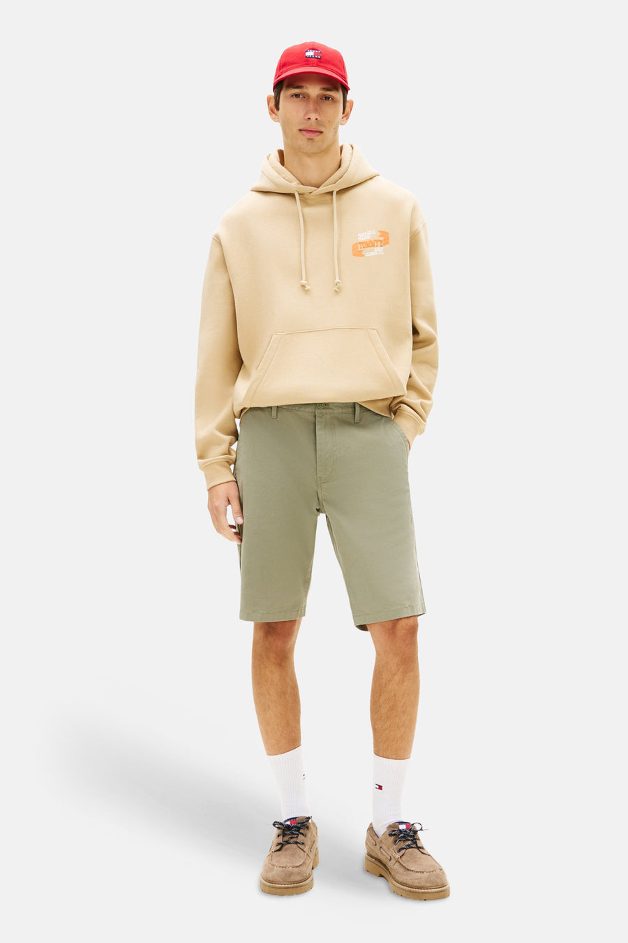 Groene short van TOMMY JEANS, gecombineerd met een beige hoodie, witte sokken en bruine schoenen.