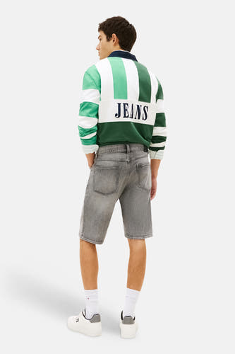 Short en jean gris en denim de TOMMY JEANS, vu de dos, avec un polo de rugby rayé et des baskets blanches.