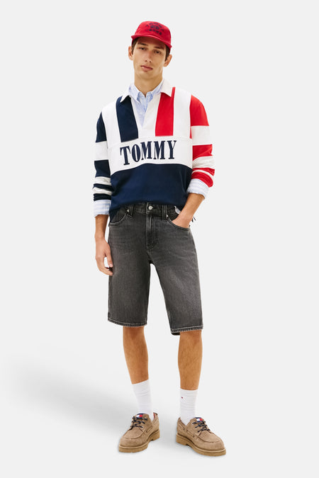 Zwarte denim short van TOMMY JEANS, met stiksels en gedragen met een rood petje, een gestreepte trui en bruine schoenen.
