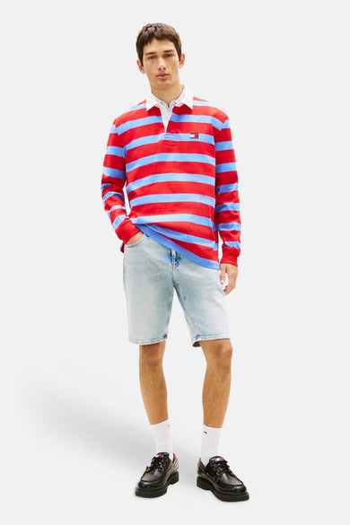 Lichtblauwe denim jeansshort van TOMMY JEANS, gedragen met een gestreept rugby shirt en zwarte veterschoenen.