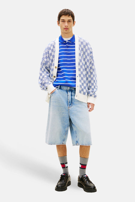 Jeansshort van denim in middenblauw van TOMMY JEANS, met wijde pijpen en zichtbare zakken, gecombineerd met een gestreepte polo en een gebreid vest.
