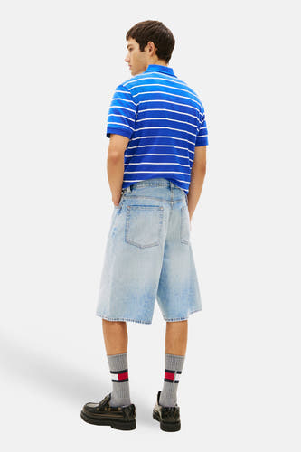 Short en jean en denim bleu moyen, de TOMMY JEANS, à jambes larges et poches apparentes, porté avec un polo rayé.